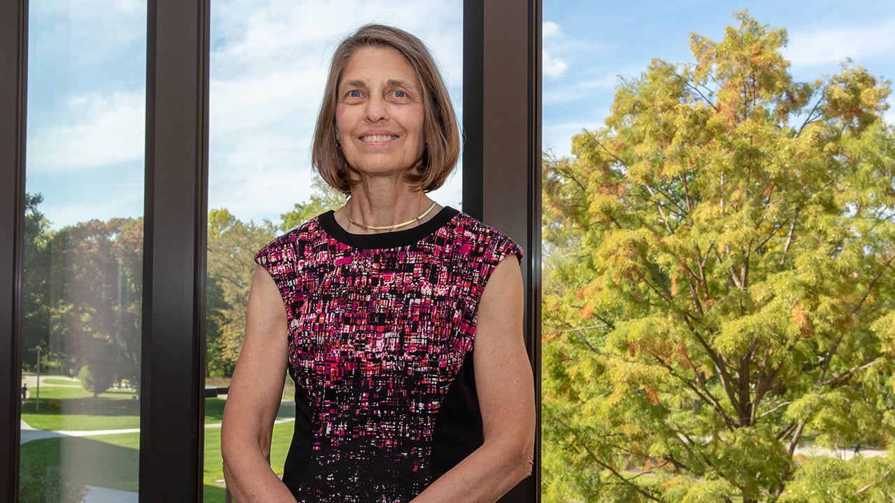 Professional image of Helen Dashney, fixed-term faculty in finance, in front of glass windows on a bright, sunny day.