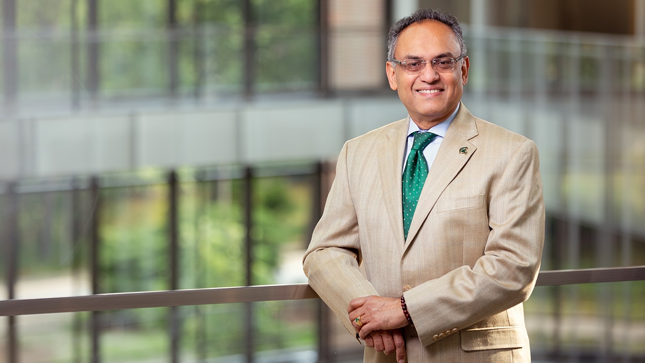 Dean Sanjay Gupta poses inside the atrium of the Edward J. Minskoff Pavilion at the Brand College of Business