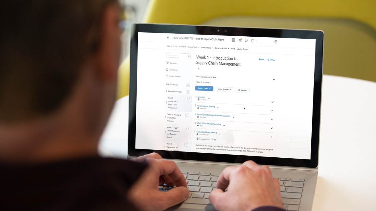 A close-up image of a man working on a laptop and navigating to an online course page.